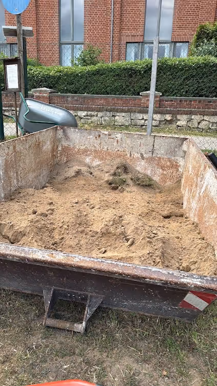 Erdaushub wird mit der Schubkarre auf einen Anhänger am Gartenweg geladen