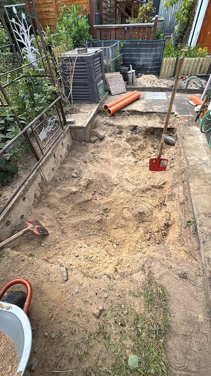 Baugrube für einen Abwassertank von Hand ausgehoben zwischen enger Bebauung