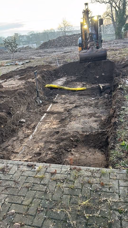 Ausgehobener Bodenstreifen entlang des Pflasterwegs, Aushub zum Abtransport bereit