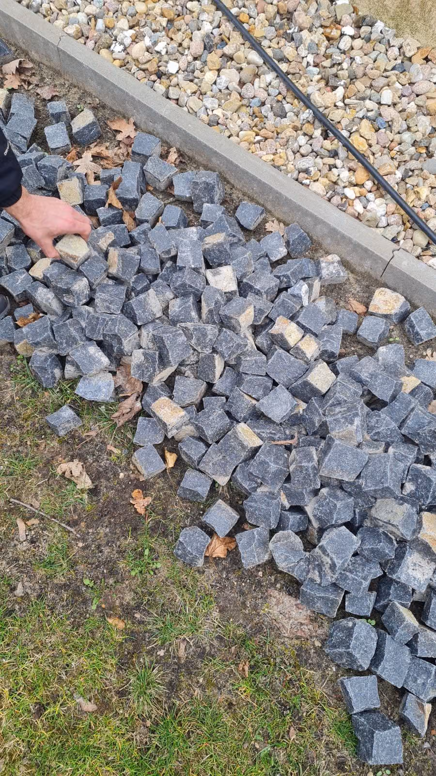 Geschütteter Haufen Basalt-Kleinpflaster auf der Baustelle vor dem Verlegen