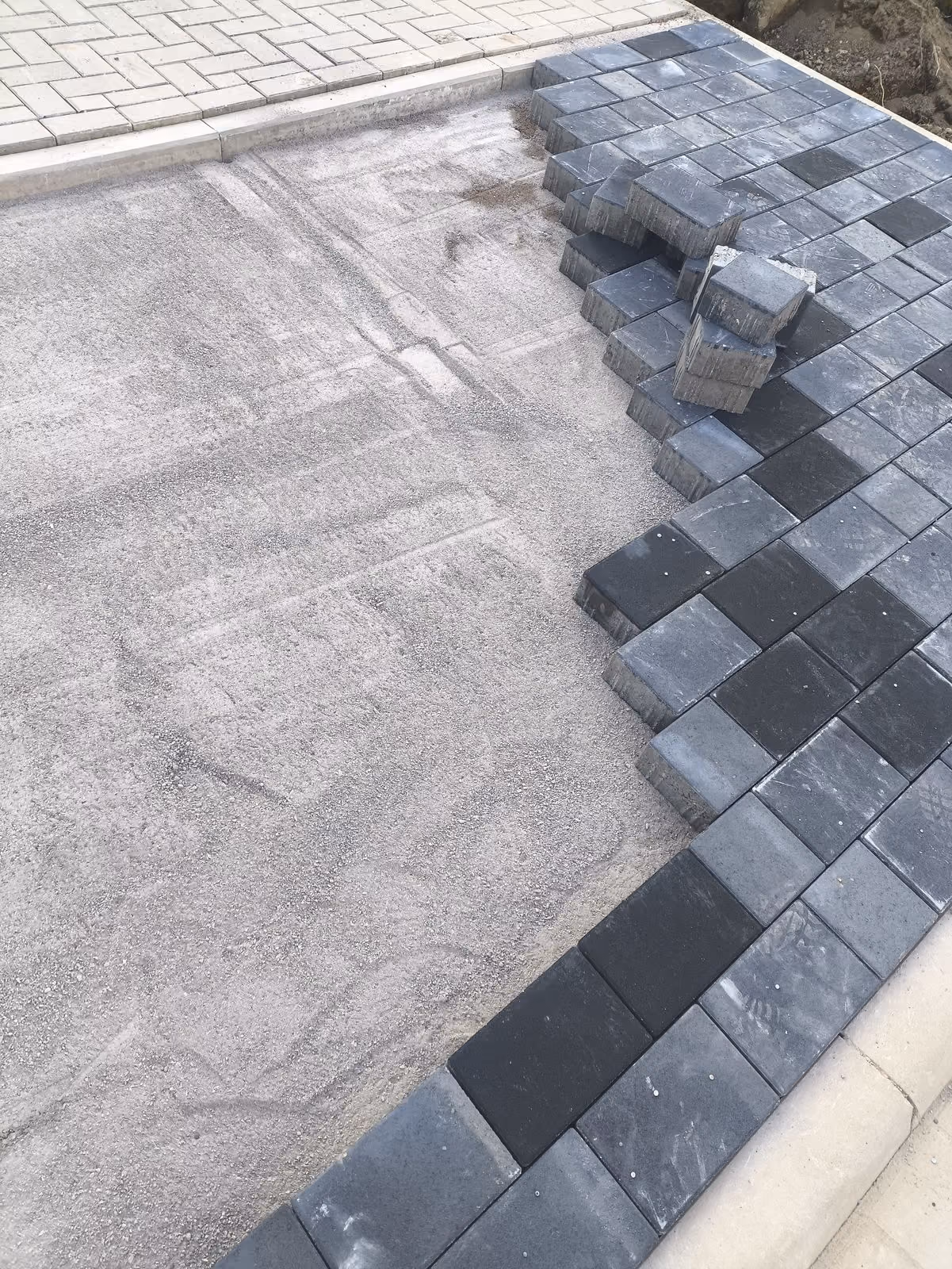 Betonpflaster in Anthrazit wird auf dem abgezogenen Splittbett verlegt