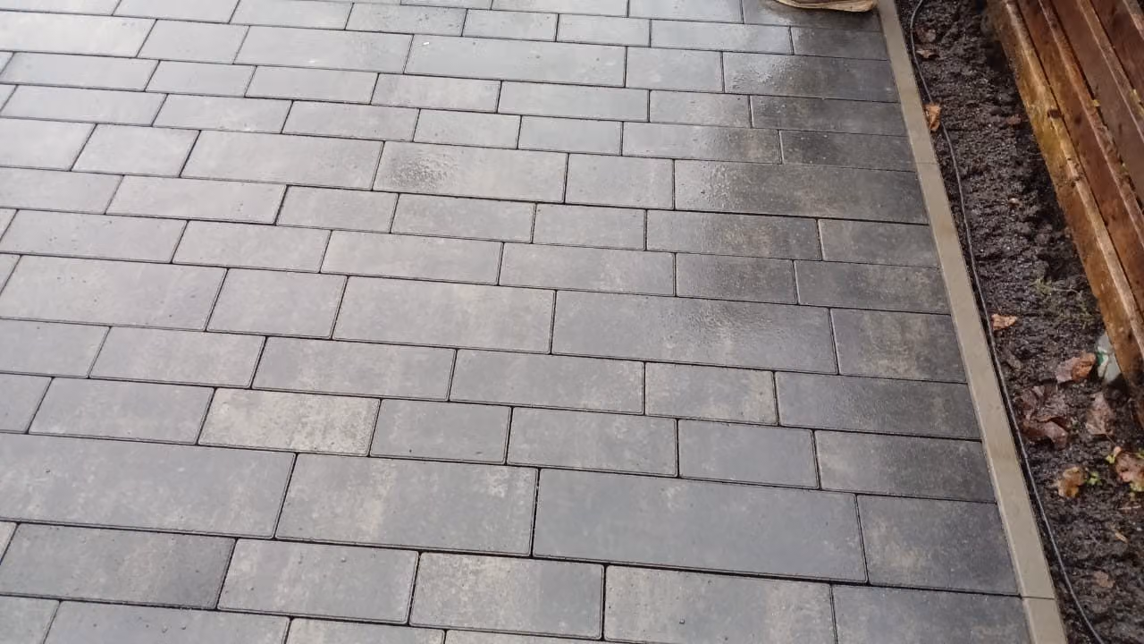 Fertige Pflasterfläche aus grauem Beton mit sauberer Randeinfassung zum Beet