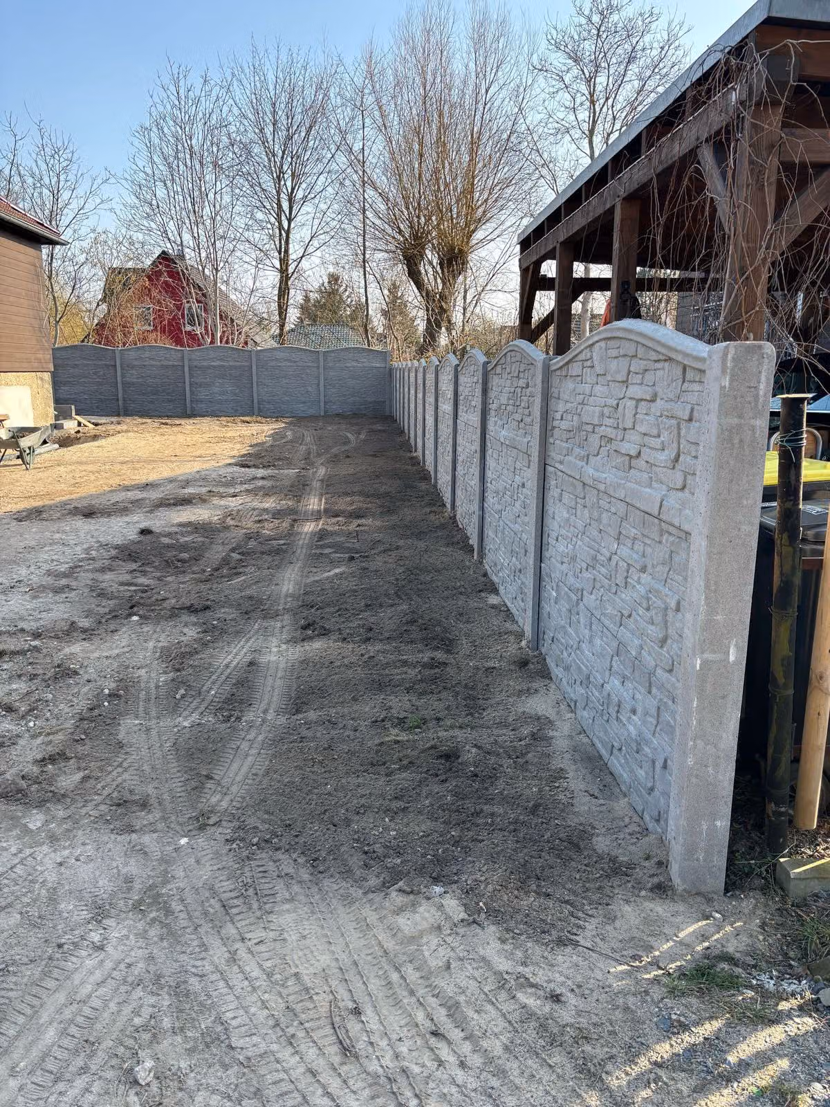 Fertig gesetzte Betonzaunreihe entlang der Grundstückskante mit ebenem Planum