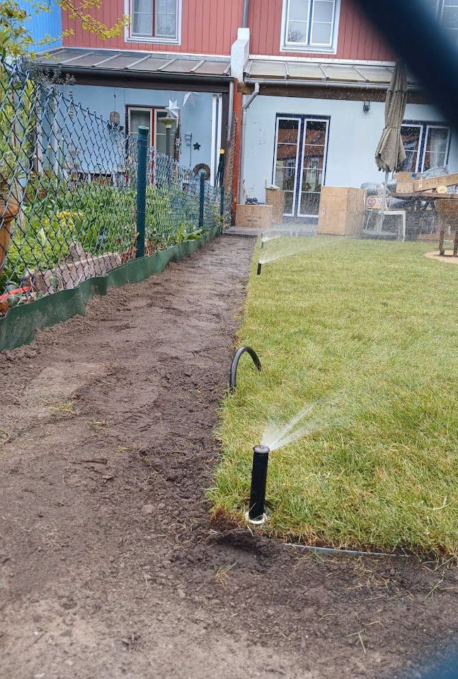 Versenkregner einer automatischen Bewässerungsanlage beim Wässern der Rasenkante