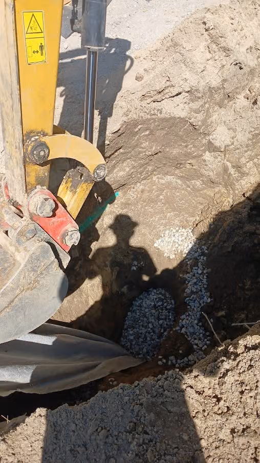 Einbau von Splitt in einen Drainagegraben mit dem Baggerlöffel