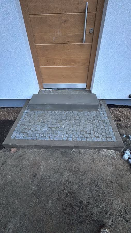 Fertiges Eingangspodest aus Granit-Kleinpflaster mit Betonstufe vor der Haustür