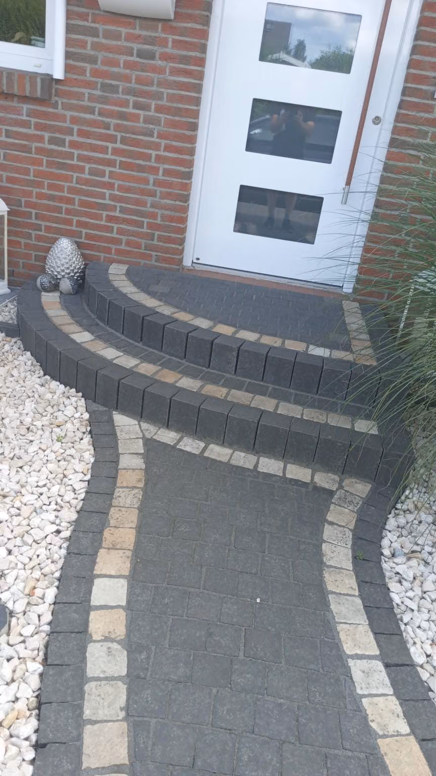 Eingangspodest mit runden Blockstufen und heller Zierzeile vor der Haustür