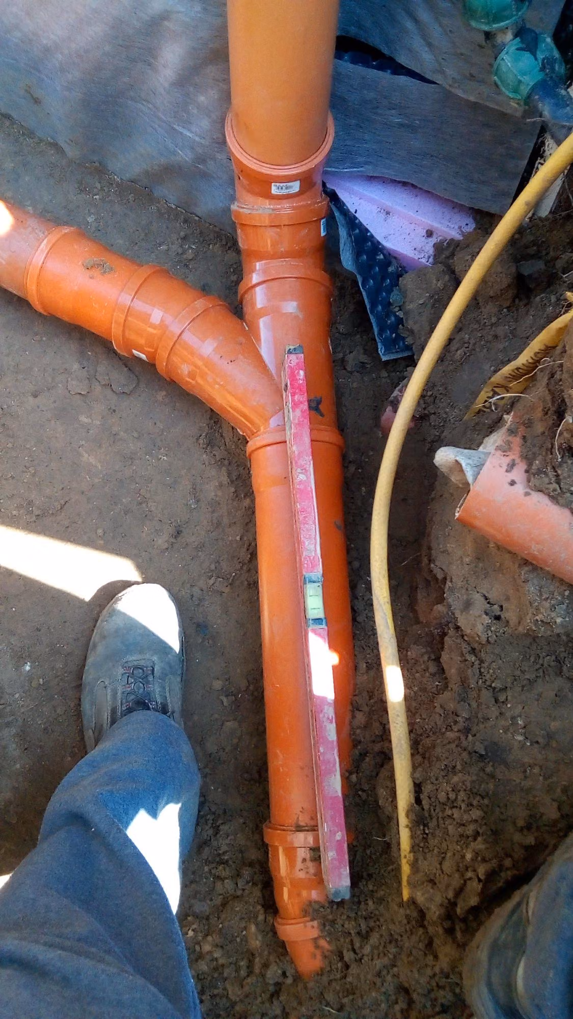 KG-Rohr-Abzweig mit Wasserwaage beim Setzen des Gefälles