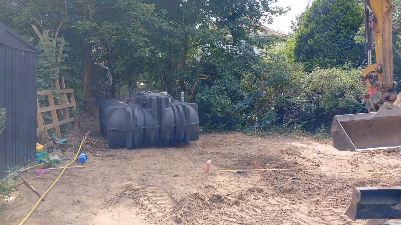 Regenwasserzisterne im Garten gesetzt, Bagger daneben im Einsatz