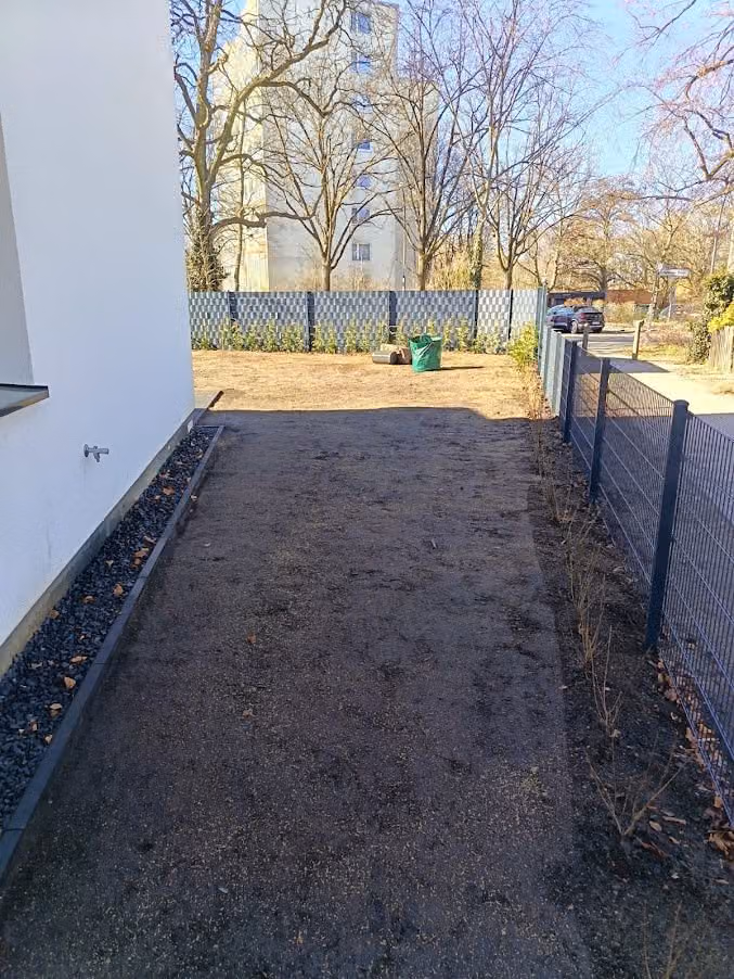 Feinplanierte Fläche entlang des Zauns, vorbereitet für die Rasenansaat