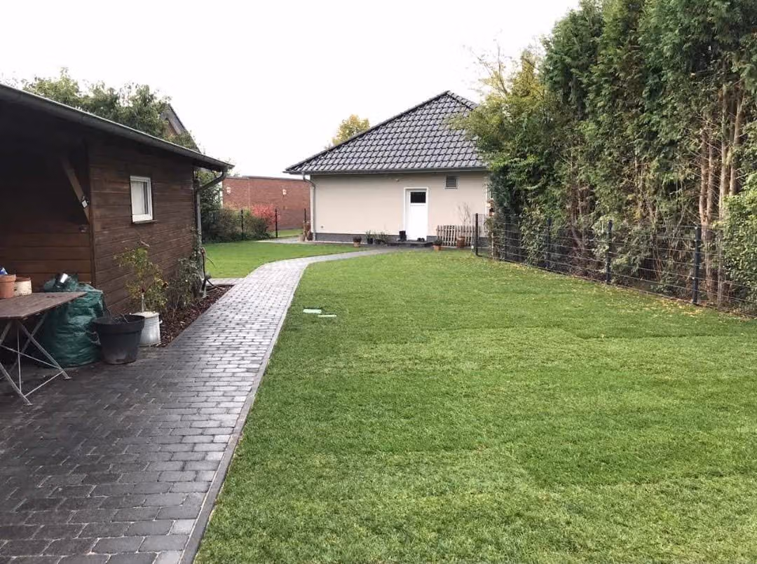 Fertiger Pflasterweg im Rasen zwischen Gartenhaus und Bungalow