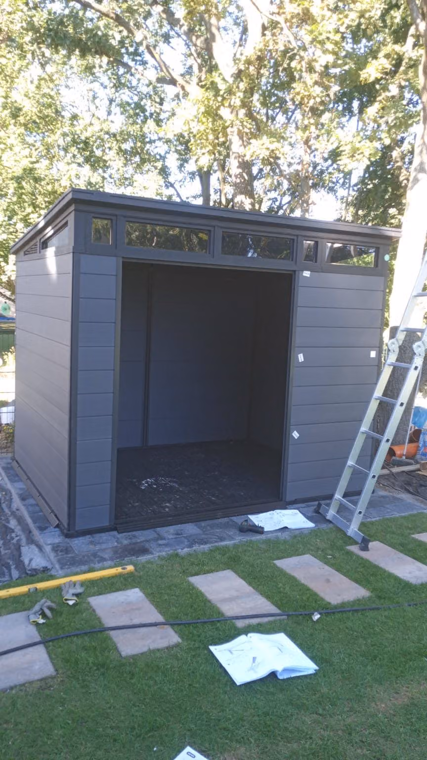Fertig aufgebautes Gerätehaus auf Plattenfundament mit Trittplattenweg im Rasen