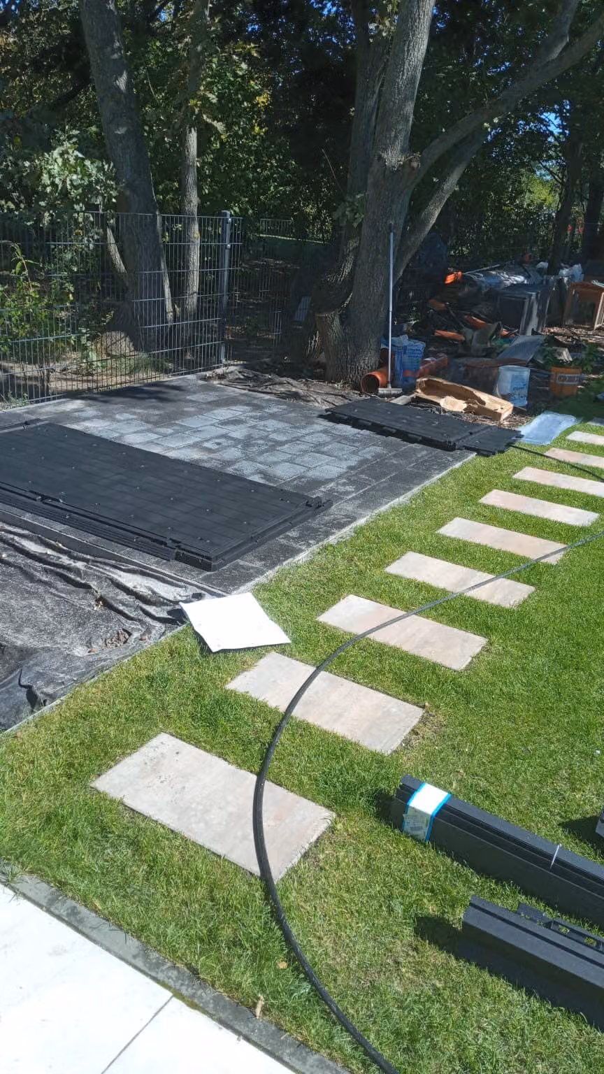 Plattenfundament für ein Gerätehaus auf Vlies, daneben ein Trittplattenweg im Rasen