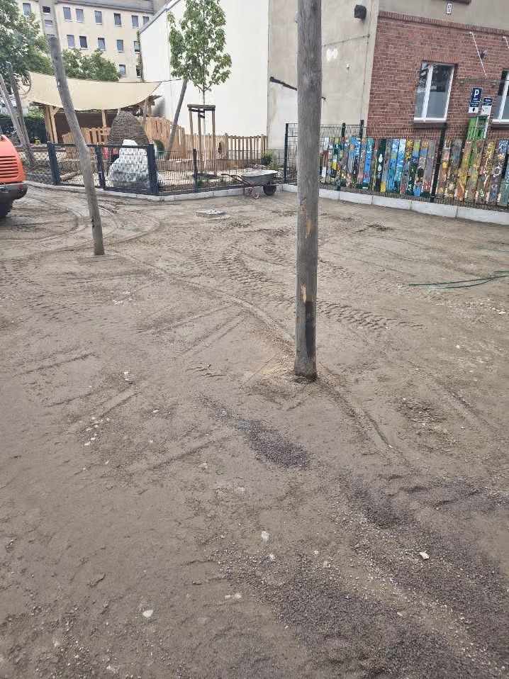 Schottertragschicht auf der Hoffläche einer Kita, Holzständer bleiben stehen