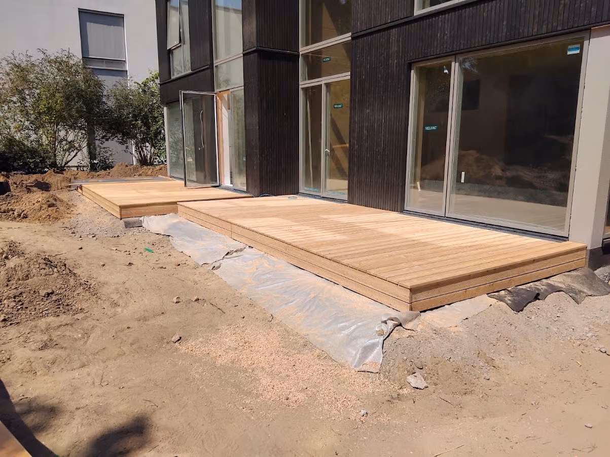 Fertige Holzterrasse aus hellen Dielen direkt an der dunklen Holzfassade