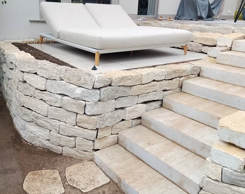 Kalkstein-Trockenmauer mit Blockstufen, oberhalb bepflanzte Böschung
