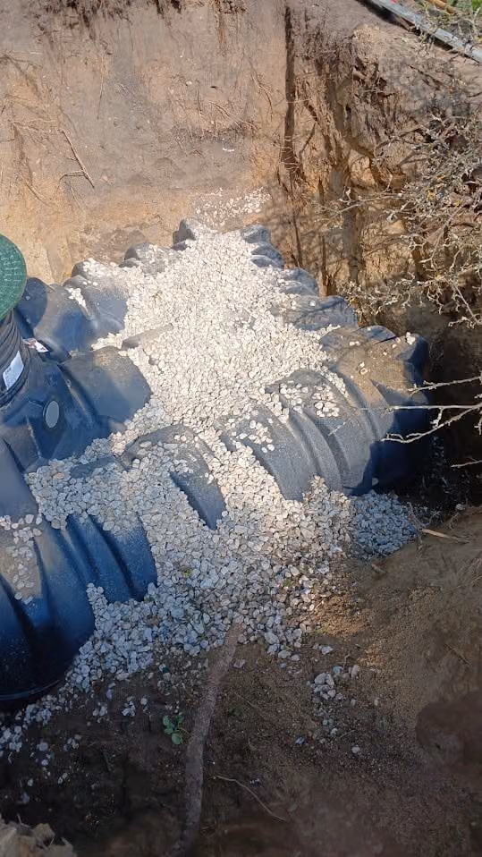 Kies wird von oben in die vorbereitete Sickerpackung neben dem Tank geschüttet