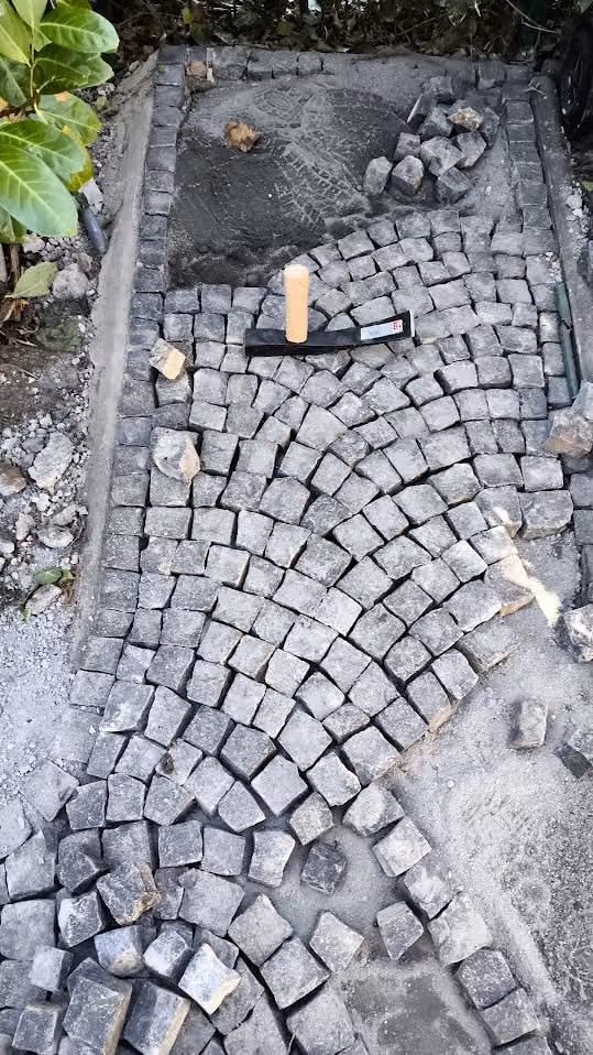 Bogenverband im Bau zwischen gesetzten Randsteinen, Werkzeug auf der Fläche