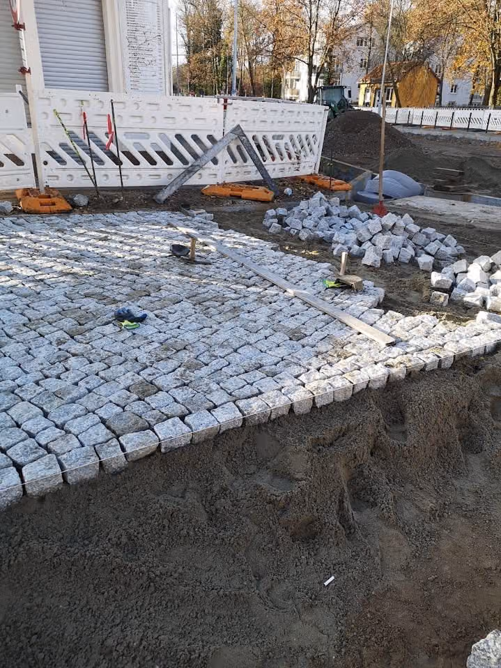 Granit-Kleinpflaster im Bogenverband während der Verlegung, Randsteine bereits gesetzt