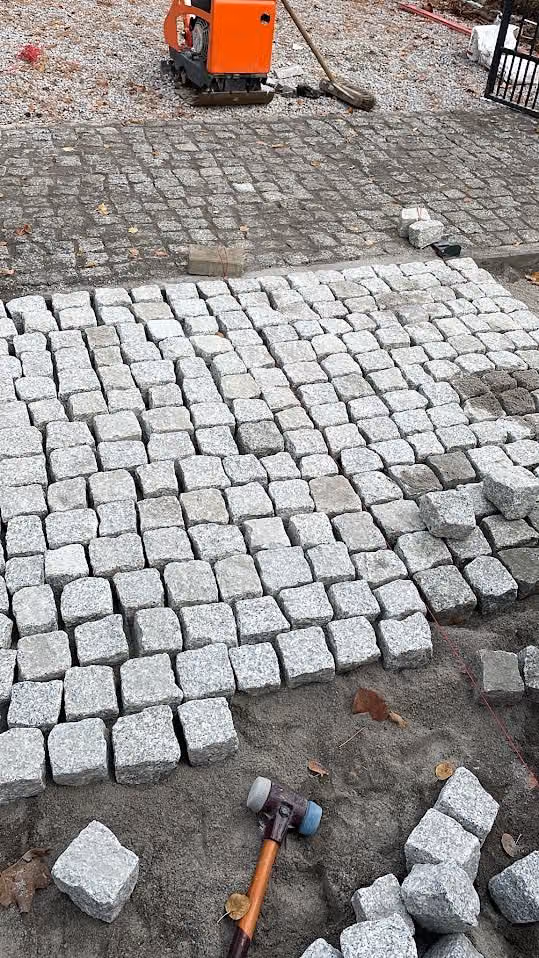 Granit-Kleinpflaster im Reihenverband während der Verlegung, Werkzeug daneben