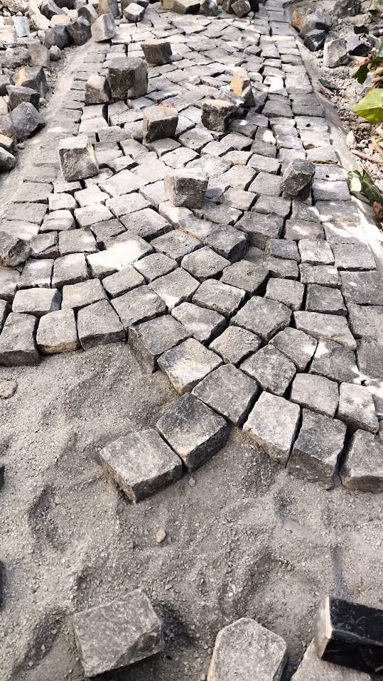 Granit-Kleinpflaster im Sandbett, Steine für die nächste Reihe bereitgelegt