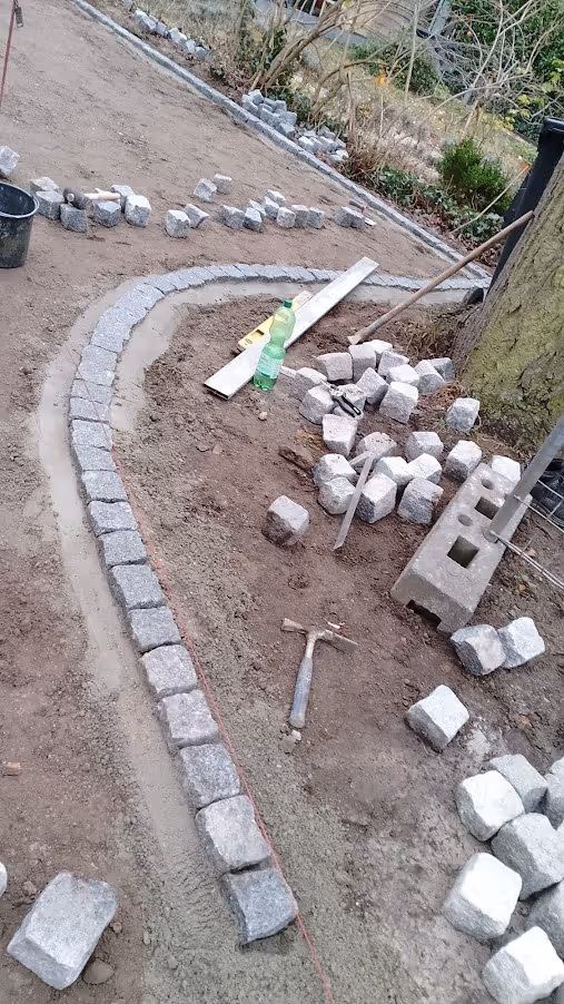 Geschwungene Kleinpflasterrinne im Bau, Steine im Betonbett verlegt