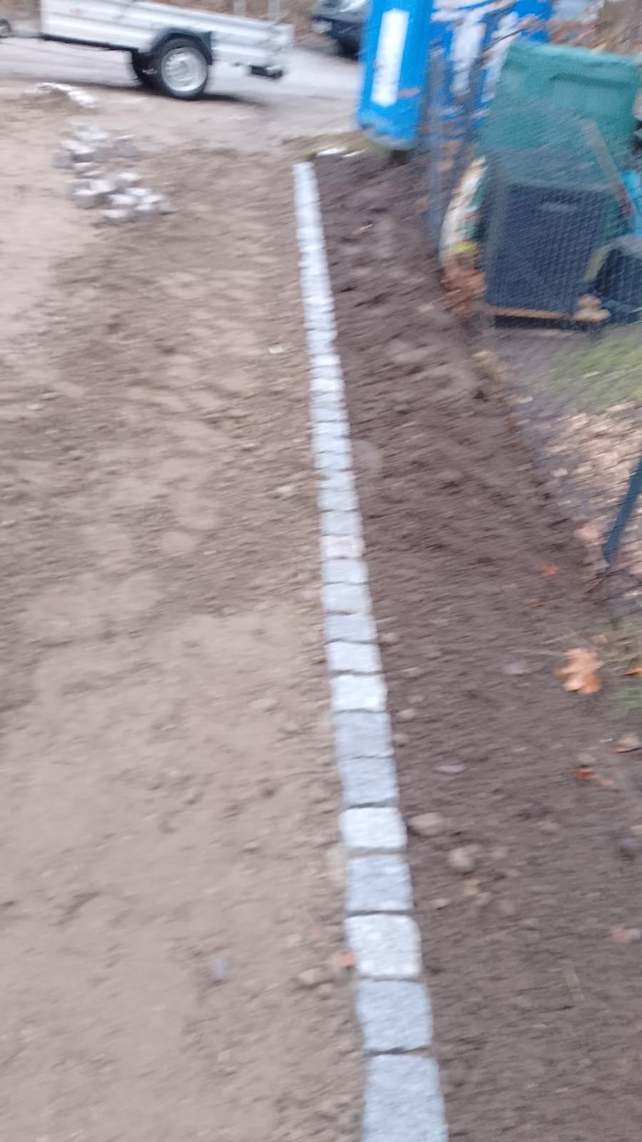 Fertig gesetzte Zeile aus Granit-Kleinpflaster als Trennung zweier Flächen