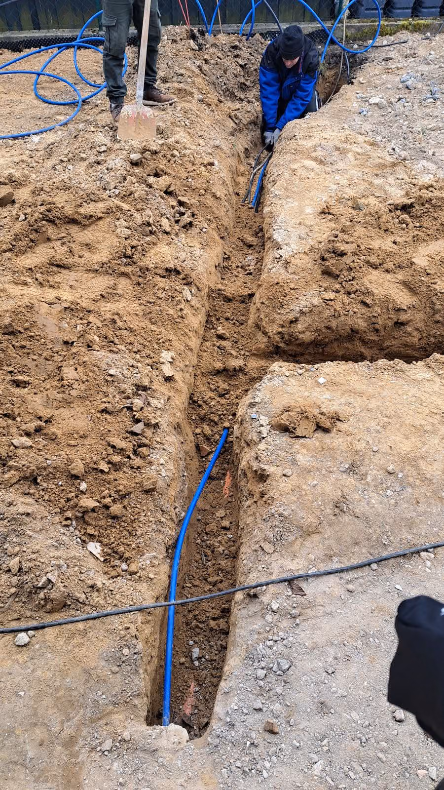 Blaues Kabelschutzrohr in der Grabensohle vor dem Verfüllen und Verdichten