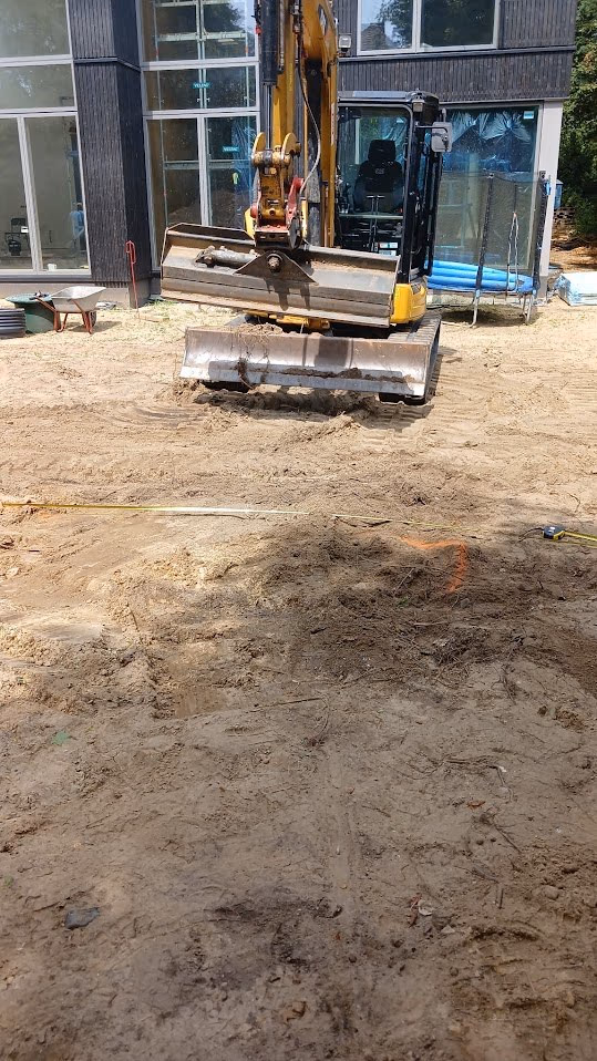 Minibagger und Plattenmaterial auf dem Sandplanum während der Bauphase