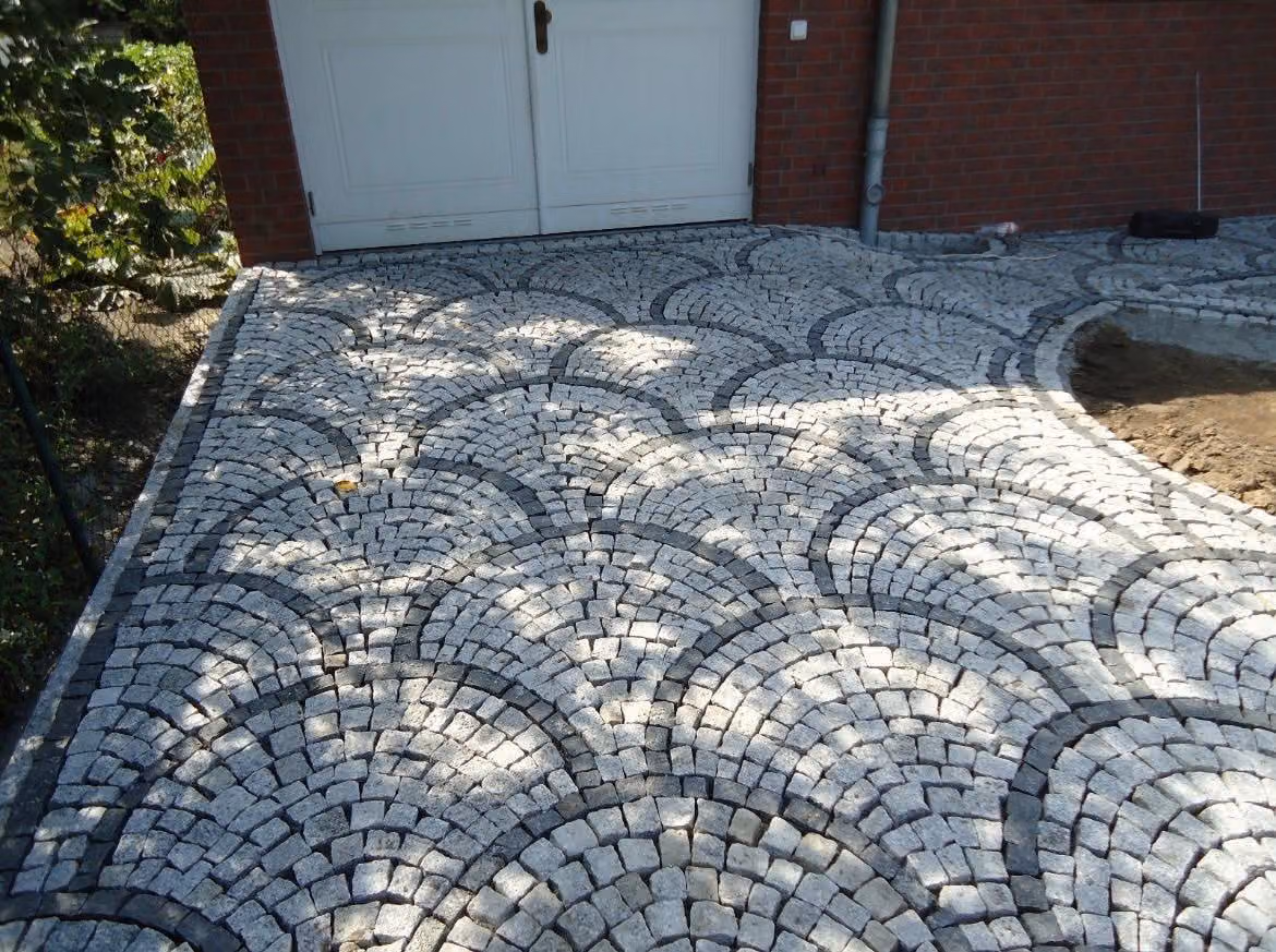 Zufahrt aus Granit-Mosaikpflaster im Segmentbogenverband vor einer Garage
