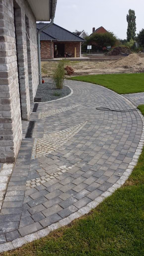 Geschwungene Pflastereinfahrt mit Granit-Einfassung und Kiesbeet