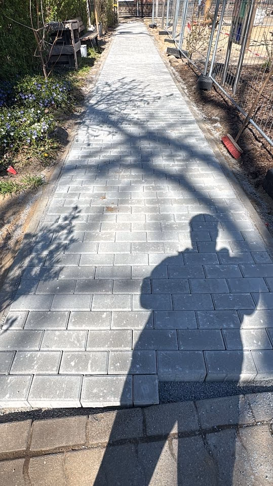 Fertiger Pflasterweg mit Randeinfassung führt durch die neu angelegte Grünanlage