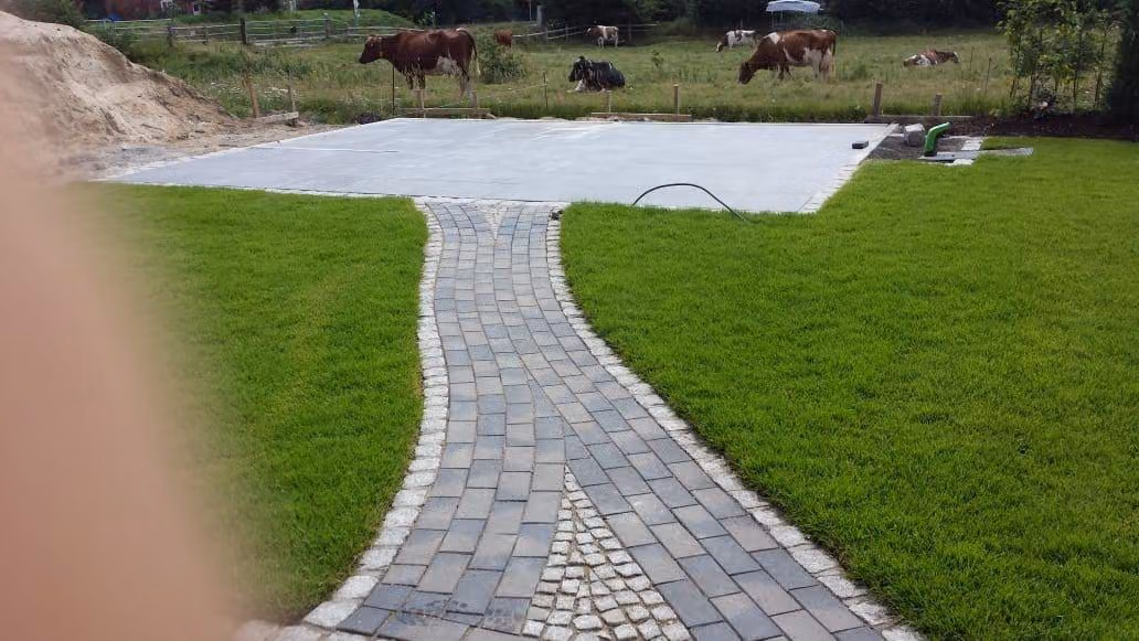 Pflasterweg mit Granit-Zeile führt über Rollrasen zur Terrassenplatte