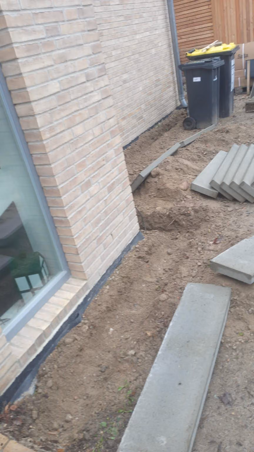 Betonplatten liegen bereit für einen Wartungsweg entlang der Klinkerfassade
