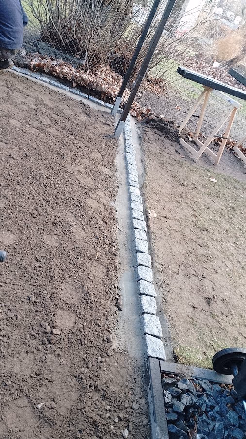 Fertig gesetzte Randeinfassung aus Kleinpflaster zwischen Beet und Rasenfläche