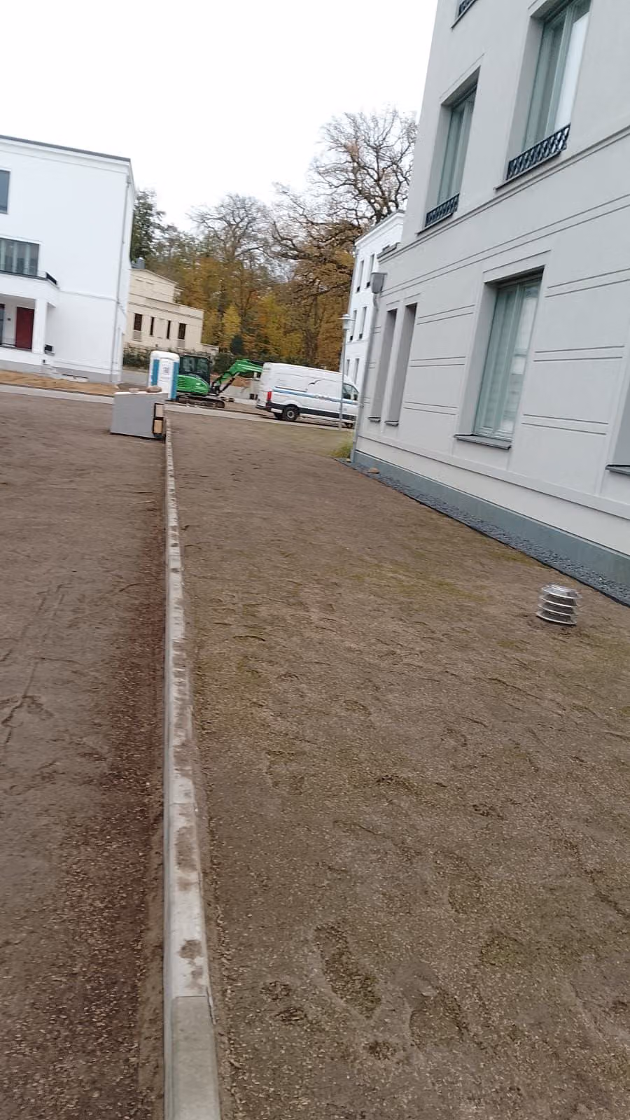 Vorbereitete Fläche mit Bordanlage zwischen zwei Gebäuden vor der Rasenansaat