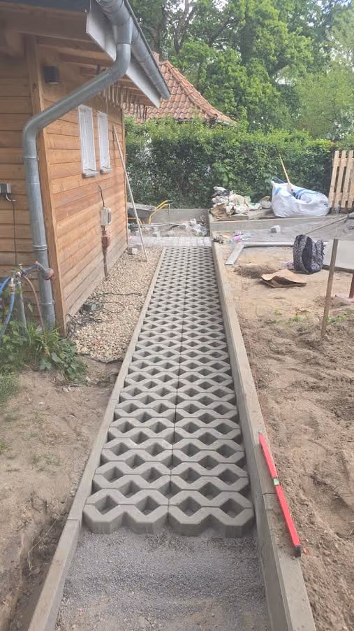 Weg aus Rasengittersteinen mit Betoneinfassung entlang des Gartenhauses