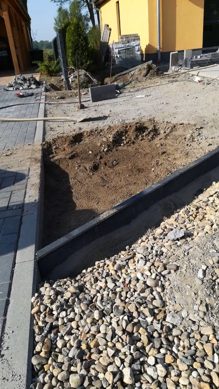 Schwarze Stahlkante zwischen Beet und Kiesstreifen, dahinter ein Pflasterweg
