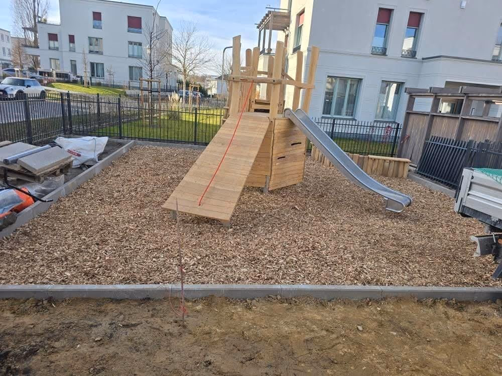 Fertiger Spielturm mit Rutsche auf Fallschutz aus Hackschnitzeln mit gesetzter Einfassung