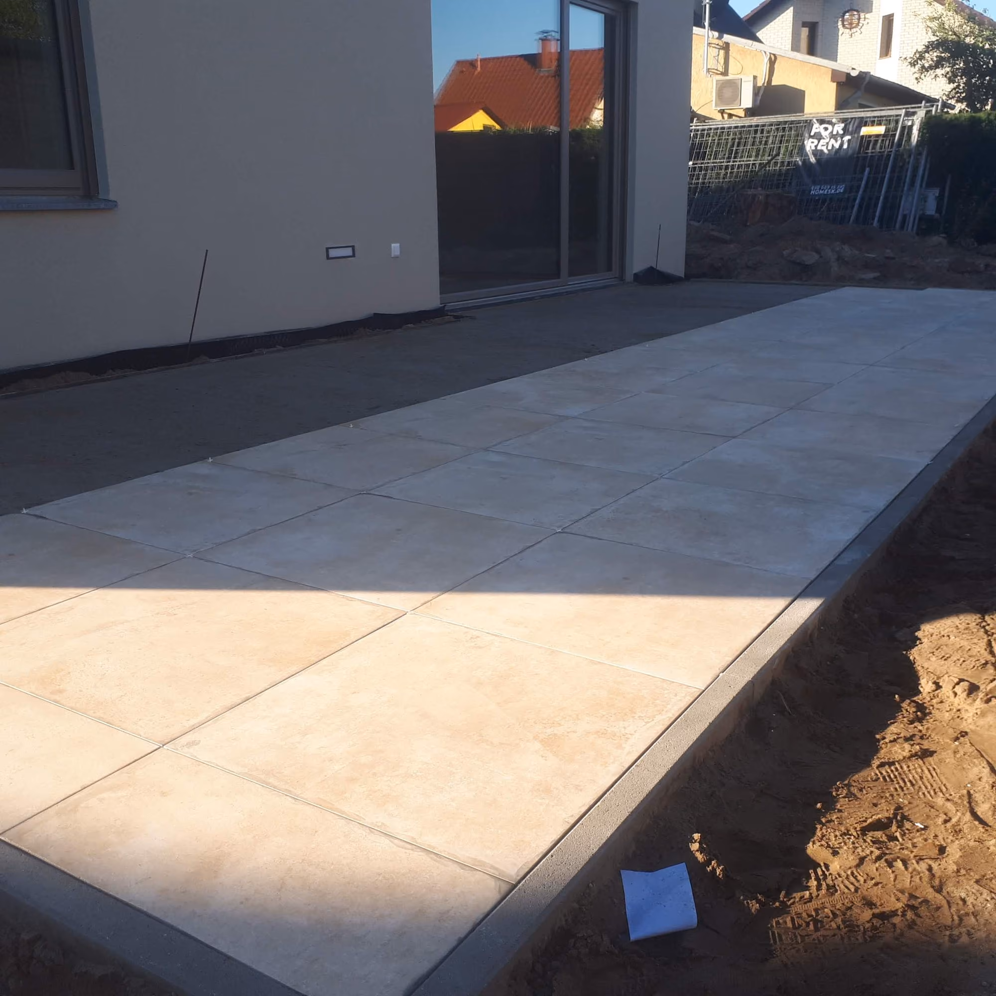 Fertige Terrasse aus großformatigen Platten mit Randeinfassung am Haus