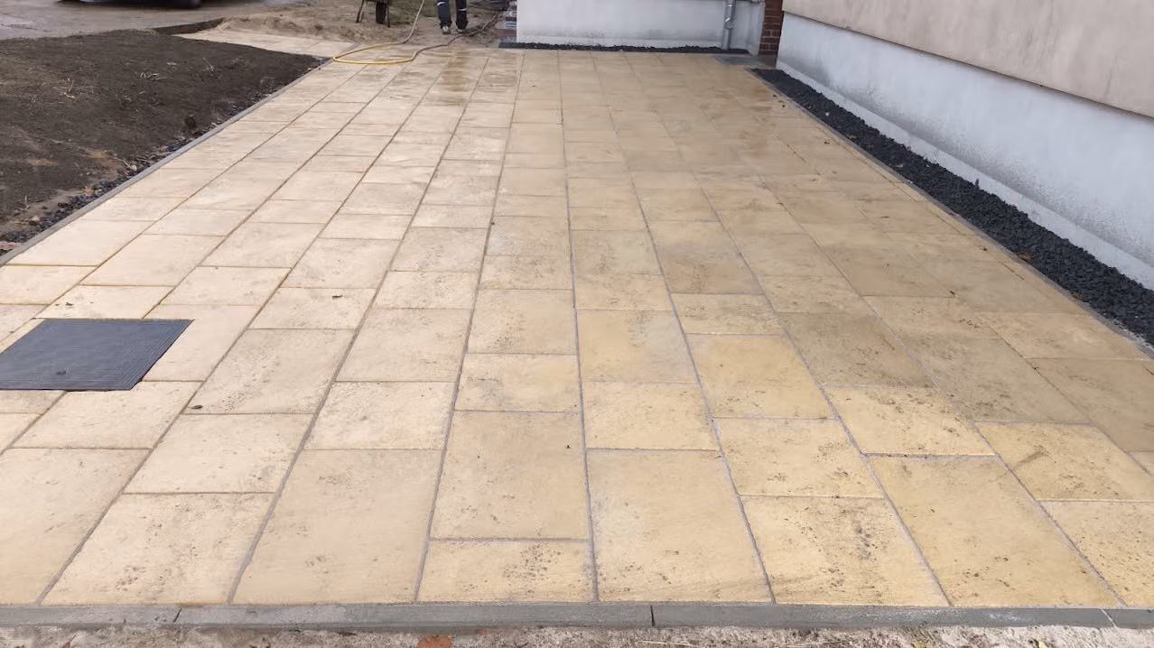 Terrasse aus großformatigen Sandsteinplatten mit Basaltsplitt-Spritzschutz an der Wand