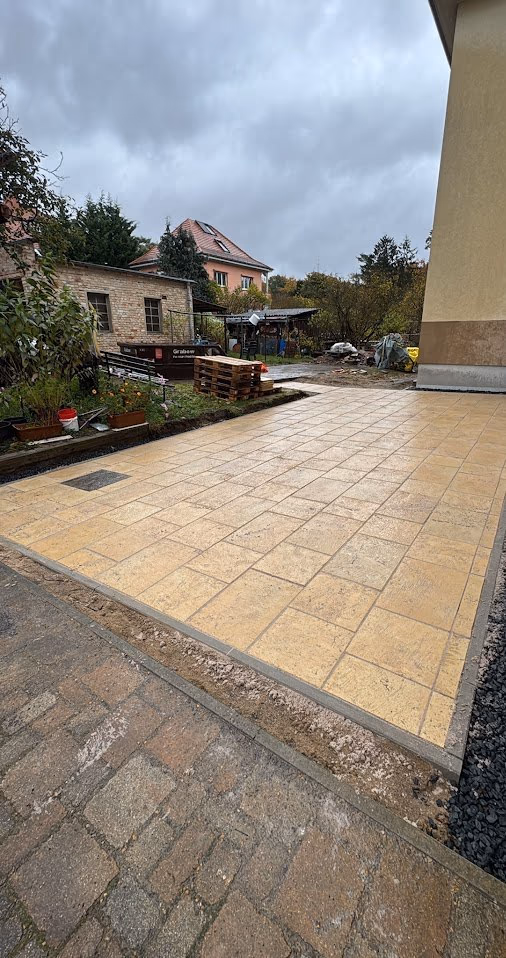 Fertige Terrasse aus hellen Travertinplatten am Haus, Randeinfassung und Kiesstreifen gesetzt
