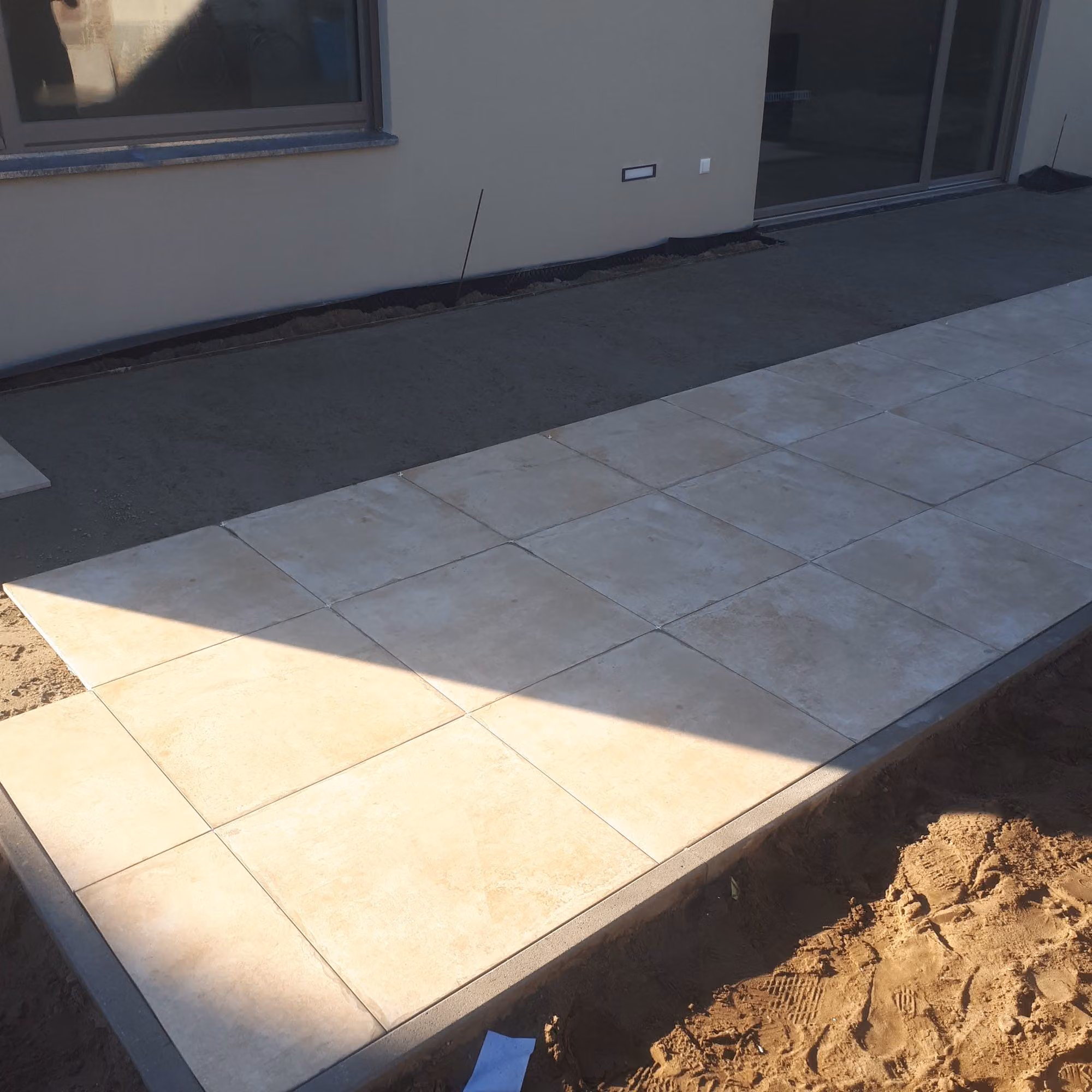 Großformatige Terrassenplatten mit sauberer Randeinfassung entlang der Hausfassade