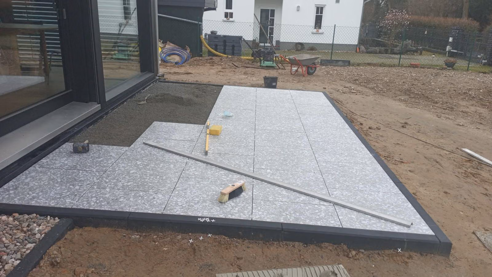 Terrazzoplatten werden mit Richtscheit und Wasserwaage auf dem Drainbett ausgerichtet