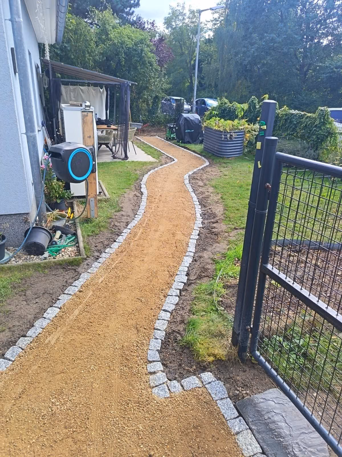 Fertige wassergebundene Wegedecke mit beidseitiger Einfassung aus Granit-Kleinpflaster