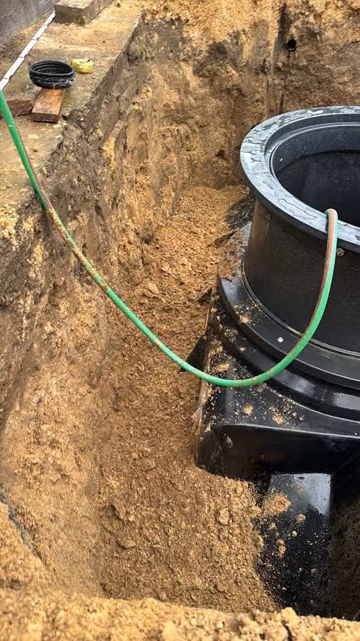 Domschacht eines Tanks im tiefen Arbeitsgraben, Zulaufleitung bereits angeschlossen
